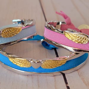 May include: Three silver bracelets with a heart and wings design. The bracelets are made with blue, pink, and turquoise ribbon.