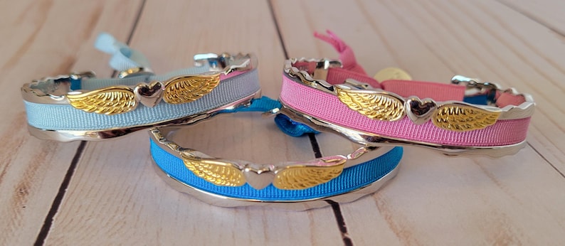 May include: Three silver bracelets with a heart and wings design. The bracelets are made with blue, pink, and turquoise ribbon.