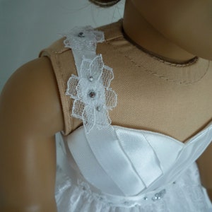 May include: A white dress with a lace bodice and a satin skirt. The bodice has a lace trim with rhinestones.
