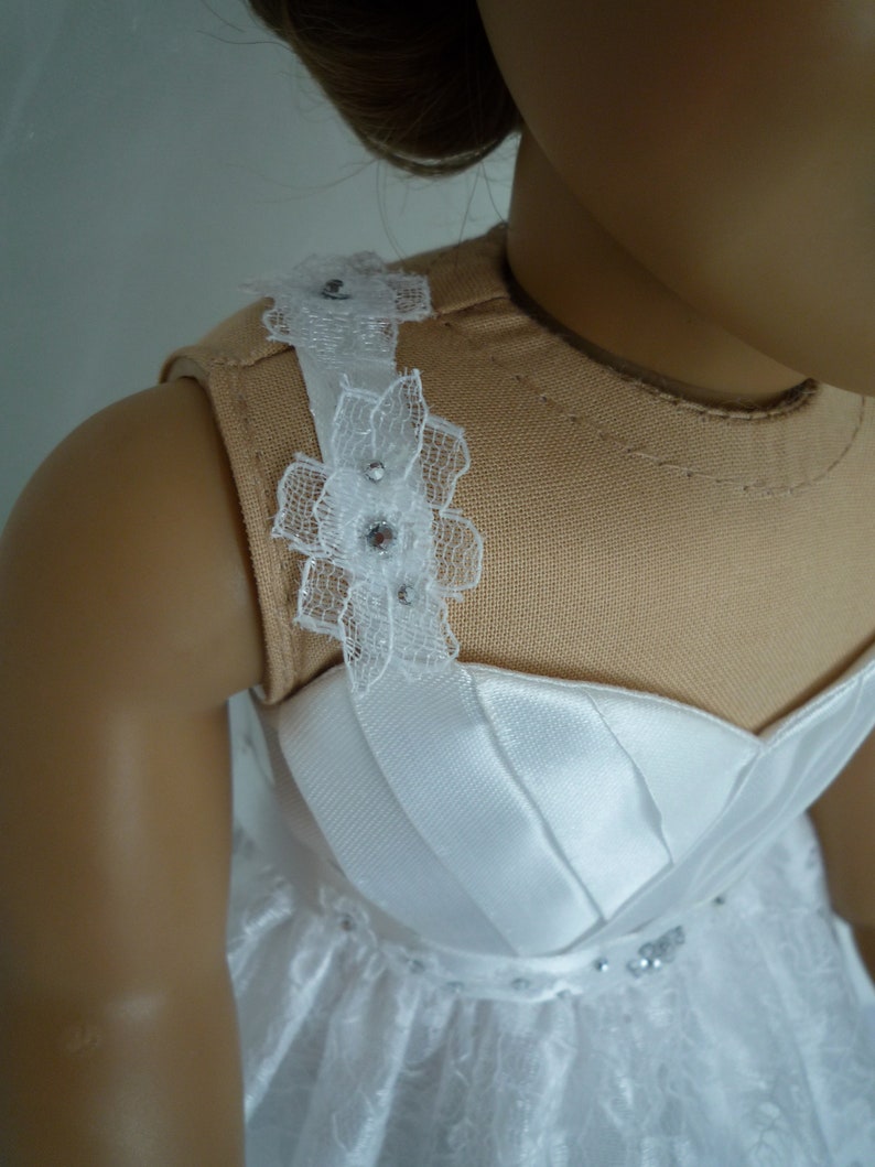 May include: A white dress with a lace bodice and a satin skirt. The bodice has a lace trim with rhinestones.