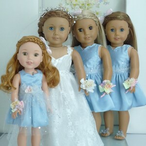 May include: Four dolls dressed in blue and white dresses. The doll in the center is wearing a white lace dress with a silver tiara. The other three dolls are wearing light blue dresses with floral embellishments.