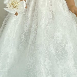 May include: White lace dress with a floral pattern. The dress has a full skirt and is made of a soft, delicate fabric.