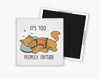 May include: A square magnet featuring a cartoon cat sleeping on a pillow. The cat is wearing a striped shirt and the text reads "IT'S TOO PEOPLEY OUTSIDE". A second black magnet is visible.