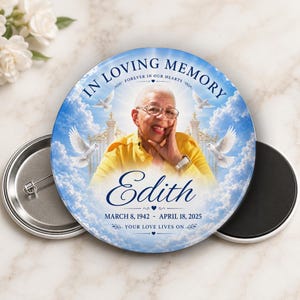 May include: A round memorial button with a photo of a smiling woman in a yellow shirt, set against a blue sky with clouds and doves. Text reads "In Loving Memory" and "Edith," with dates March 8, 1942 - April 18, 2025. The phrase "Your Love Lives On" is also included.
