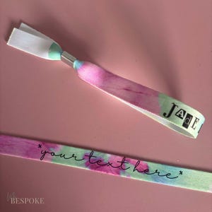 May include: Two tie-dye fabric wristbands. One wristband has the name "JADE" printed on it. The other wristband has the text "*your text here*" printed on it.
