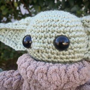Puede incluir: Mu&ntilde;eco de ganchillo con grandes ojos negros y grandes orejas puntiagudas. La cabeza y las orejas son de color verde claro, con un cuerpo gris difuso. El mu&ntilde;eco est&aacute; hecho a mano y representa un personaje popular.