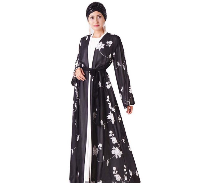 May include: A black long-sleeved robe with white floral embroidery and a matching black sash. The robe is open in the front and has a flowing silhouette.