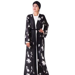 May include: A black long-sleeved robe with white floral embroidery and a black sash. The robe has a white lining and is open in the front.