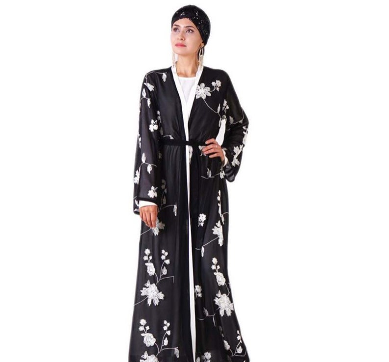 May include: A black long-sleeved robe with white floral embroidery and a black sash. The robe has a white lining and is open in the front.