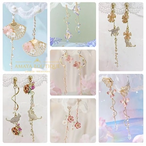 May include: A set of 10 pairs of delicate gold dangle earrings featuring floral, butterfly, and cat designs. The earrings are adorned with pearls, crystals, and colourful enamel.