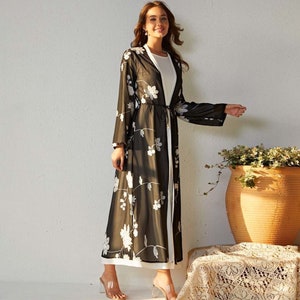 May include: A long black sheer cardigan with white floral embroidery. The cardigan has a tie at the waist and long sleeves.