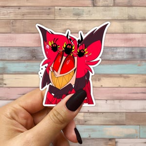 May include: A red and black cartoon character with horns and a wide grin. The character has red eyes with black circles around them. The character is wearing a black bow tie and a red jacket.