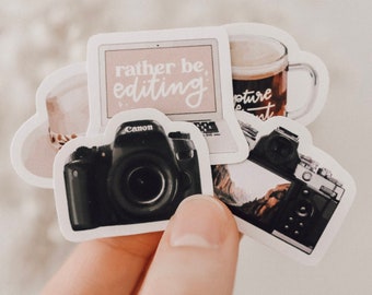 May include: A set of four stickers featuring a camera, a laptop with the text "rather be editing", a coffee cup with the text "capture the moment", and a mug with a brown liquid.
