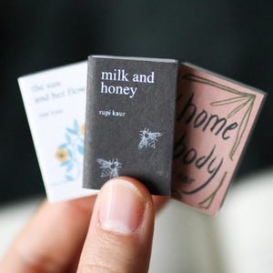 Peut inclure: Ensemble de trois mugs en céramique avec une finition mate et mouchetée. Les tasses sont de couleur crème, gris clair et gris foncé. Chaque mug a un design simple et minimaliste.