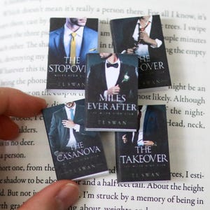 May include: A white ceramic mug with a black handle and the text "But First, Coffee" in a bold, black font. The mug is set against a blurred background, suggesting a cozy setting.