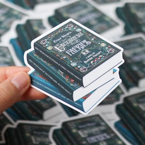 May include: Three stickers depicting book designs, stacked on top of each other. The top sticker reads "Emily Wilde's Encyclopaedia of Faeries". The other stickers have similar titles. The books have dark green covers with white borders.