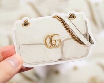 May include: White leather handbag with a gold chain strap and a gold GG logo.