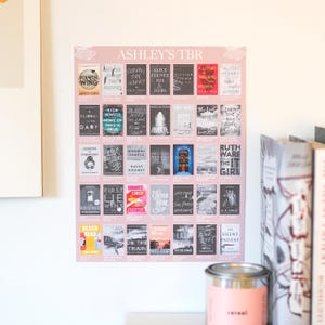 Könnte beinhalten: Ein rosa Poster mit der Aufschrift "ASHLEY'S TBR" mit einem Raster von Buchcovern. Das Poster zeigt verschiedene Buchtitel und Autoren, darunter "Fourth Wing", "The Night" und "Lessons in Chemistry". Ein dekorativer Gegenstand ist unten sichtbar.