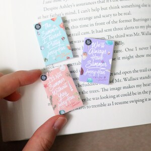 May include: Three small book-shaped stickers with pastel backgrounds and seashell illustrations. The stickers feature titles like "The Summer I Turned Pretty" and "We'll Always Have Summer" by Jenny Han.