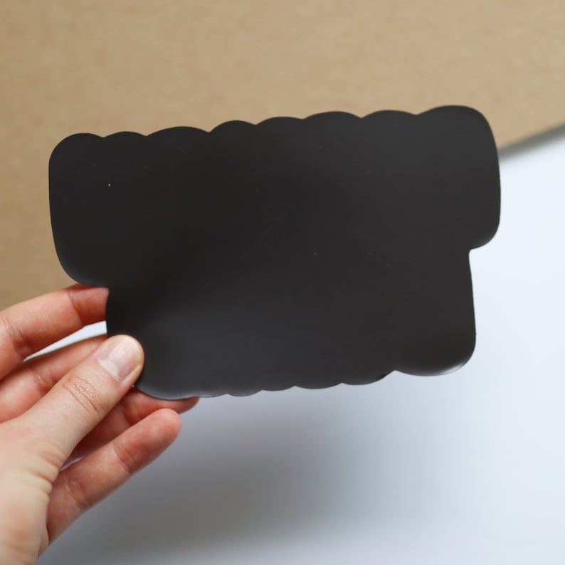 May include: A black, flexible, magnetic sign with a wavy edge. The sign is blank and ready to be written on.