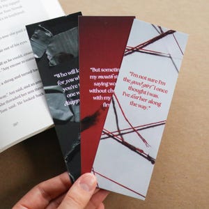 Op de afbeelding: Drie rechthoekige bladwijzers met citaten. Eén is zwart met witte tekst, een andere is bordeauxrood met witte tekst, en de derde is wit met rode tekst en een rood lijnenontwerp.