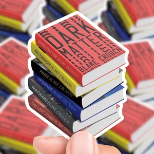 May include: A stack of Blake Crouch book stickers. The top book is red with the title "Dark Matter." Other titles include "Recursion," "Pines," "Upgrade," "Wayward," and "The Last Town." The stickers have white borders.