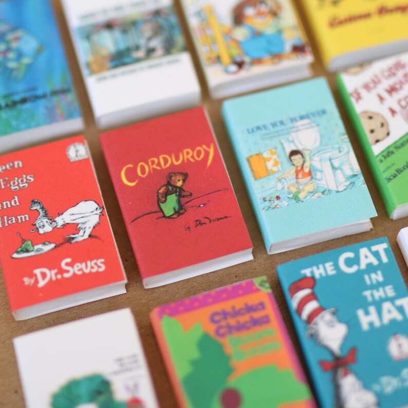May include: A collection of miniature children's books with colorful covers. Titles include "Corduroy", "The Cat in the Hat", and "Green Eggs and Ham" by Dr. Seuss. The books are arranged closely together, showcasing various illustrations and text.