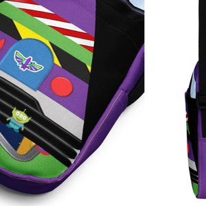 Puede incluir: Bolso bandolera morado y azul con un dise&ntilde;o de nave espacial de dibujos animados. La nave espacial tiene un personaje alien&iacute;gena verde, un bot&oacute;n rojo y una franja amarilla y negra. El bolso tiene una correa ajustable negra.