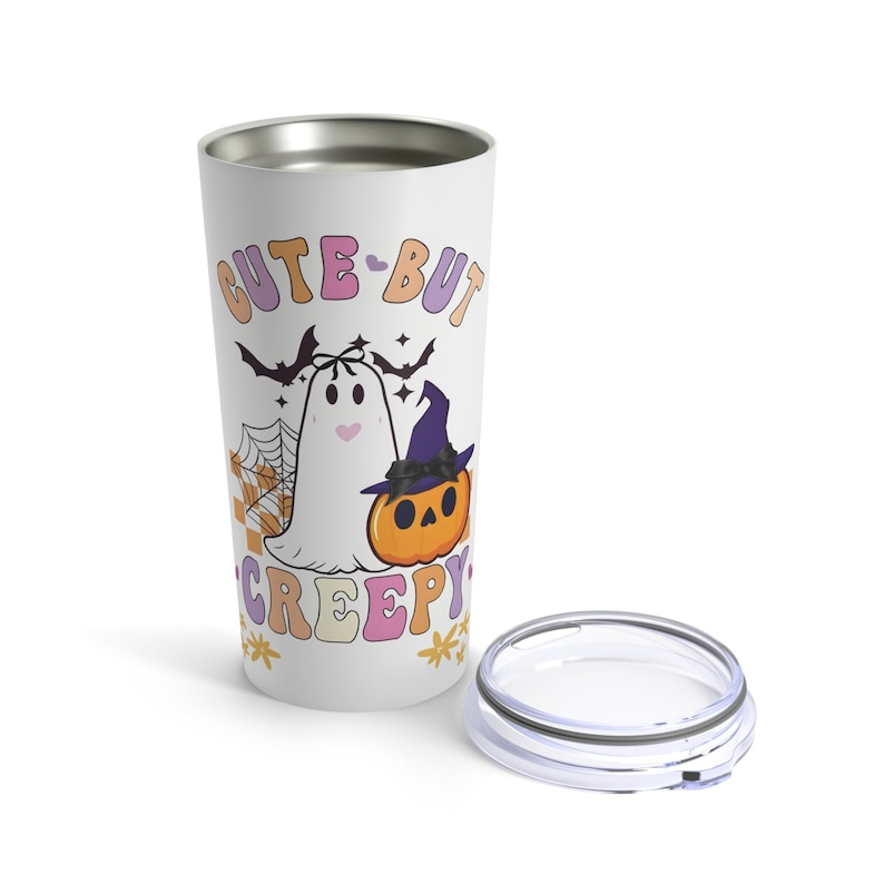 K&ouml;nnte beinhalten: Ein wei&szlig;er Edelstahlbecher mit einem niedlichen Geister- und K&uuml;rbisdesign. Der Text "Cute-But Creepy" ist in rosa, lila und orangefarbenen Buchstaben gedruckt.