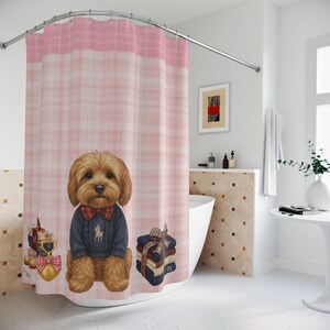 May include: A pink and white plaid shower curtain featuring a brown dog wearing a blue sweater and a red bow tie. The dog is surrounded by gifts and towels. The top of the curtain is a solid pink color.