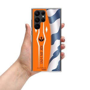 May include: A clear phone case with an orange and white design featuring the Star Wars character Ahsoka Tano. The case has a quote "I am no Jedi" and the character's name "Ahsoka Tano".