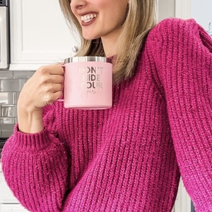 May include: A woman wearing a pink sweater with glitter holds a pink travel mug with the text "Don't Hide Your Sparkle".