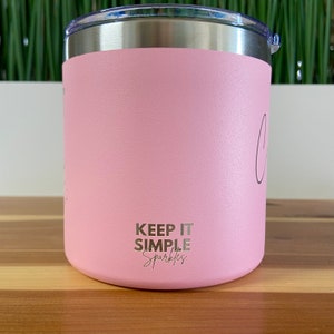 May include: A pink stainless steel tumbler with a silver lid. The tumbler has the text "Keep it simple sparkles" printed on the bottom.
