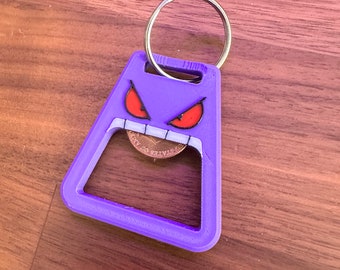 Peut inclure: Porte-clés en forme de fantôme de dessin animé imprimé en 3D de couleur violette avec des yeux rouges et une bouche. Le porte-clés a un ouvre-bouteille intégré dans la bouche et un anneau de clé argenté.