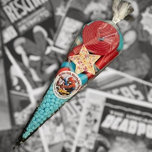 May include: A cellophane cone filled with blue sweets, red liquorice, and a star-shaped sweet. A round sticker with Spider-Man is on the cone. The text on the sticker reads "Myle's 4th Birthday Party. Thank you for coming!"