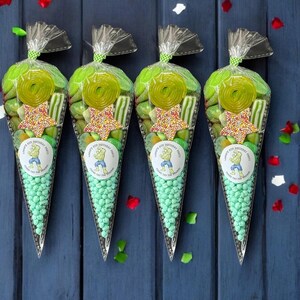 May include: Four transparent cone-shaped bags filled with green sweets, including gummy rings, star-shaped sprinkles, and round mints. Each bag has a circular sticker with a cartoon character and the text "Happy 4th Birthday Party". The bags are tied with a silver twist tie.
