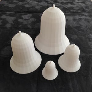 Può includere: Quattro campane in ceramica bianca di diverse dimensioni. Le campane hanno tutte la forma di una campana tradizionale con una parte superiore arrotondata e una parte inferiore svasata. Le campane sono disposte a forma di piramide, con la campana più grande in cima e la campana più piccola in fondo.