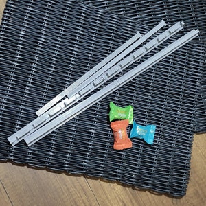 May include: Three packs of individually wrapped candy on a black woven placemat. The candy is green, orange, and blue. The placemat is made of woven plastic.