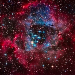 May include: A vibrant nebula with a red and blue glow, filled with countless stars. The nebula is surrounded by a dark, swirling cloud of gas and dust.