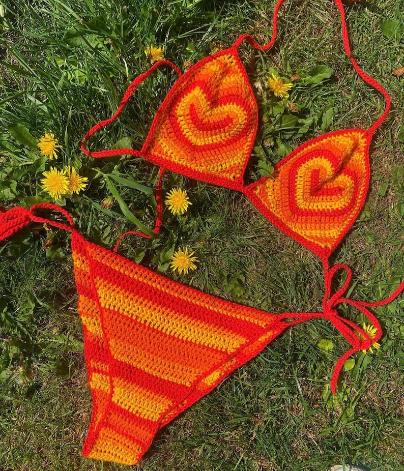 May include: A crocheted bikini top and bottom in a red and yellow striped pattern. The top is a triangle style with a tie at the neck and back. The bottom is a high-waisted style with ties on the sides.