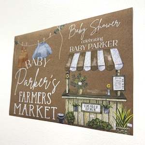 May include: A brown card with the text "Baby Shower celebrating BABY PARKER" and "Baby Parker's FARMERS MARKET". The card features illustrations of baby clothes on a clothesline and a farmer's market stand with plants.