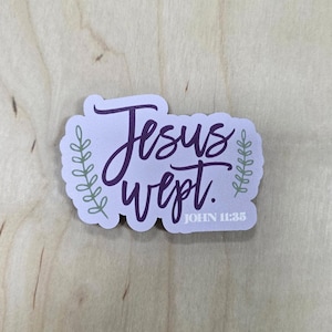 May include: A sticker with the words "Jesus wept." in a cursive, purple font. The sticker has a light purple background with green leaf accents and the text "JOHN 11:35" in a smaller font.