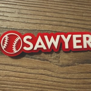 May include: Red and white baseball keychain with the name "SAWYER" in white lettering.