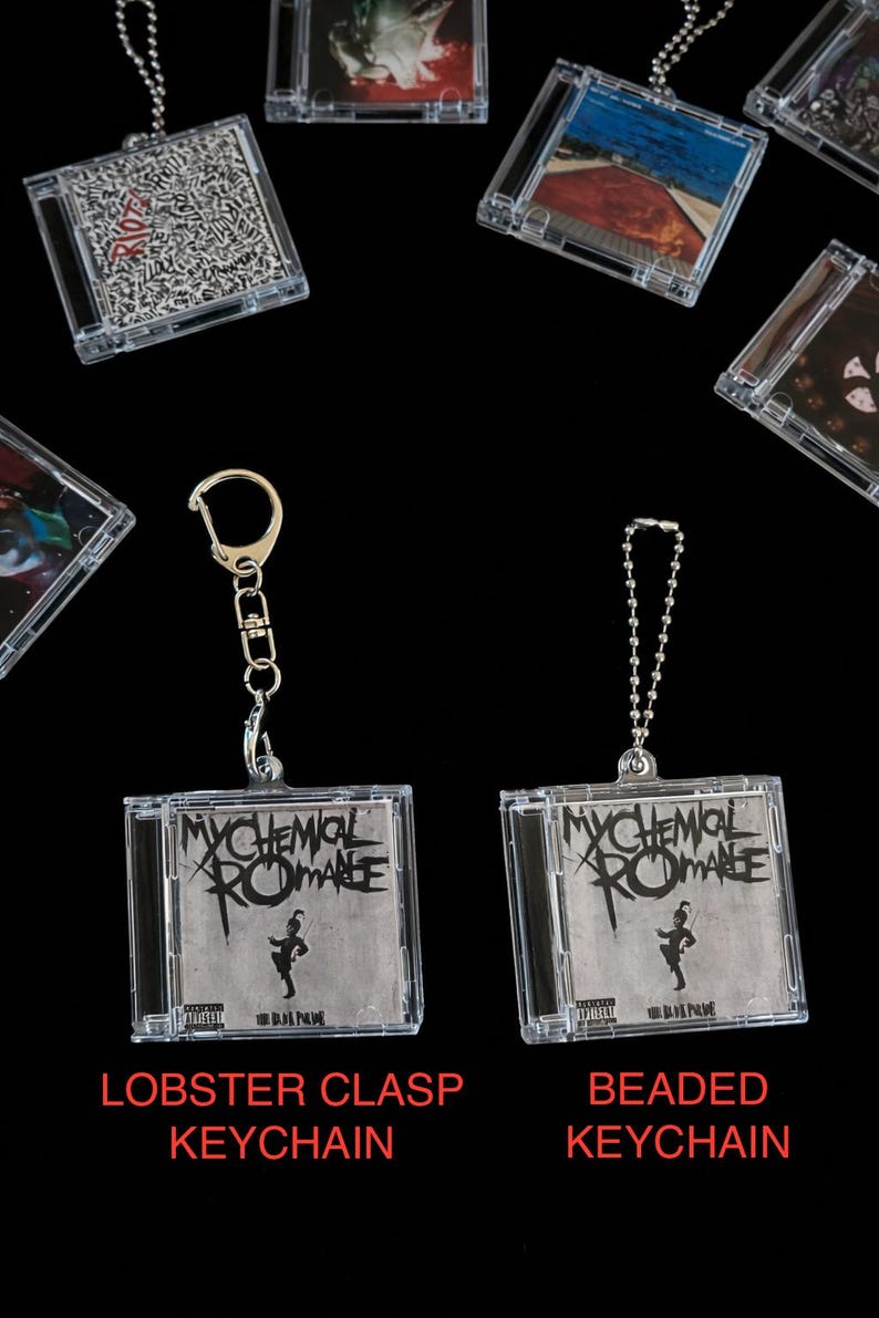 May include: Clear plastic keychain featuring a miniature CD case with the band name "My Chemical Romance" in black and white. The keychain is available with a lobster clasp or beaded chain. Other CD case keychains are also visible.