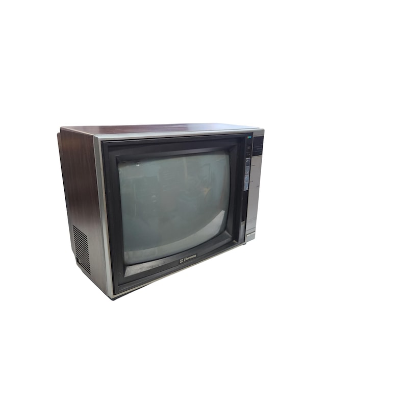 May include: A retro television set with a wood-effect casing and a dark screen. The TV has a silver trim around the screen and a control panel on the right. The brand name is visible on the bottom left of the screen.
