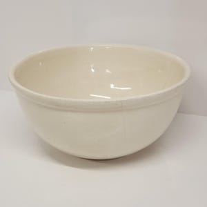 May include: A large, white ceramic mixing bowl. The bowl is round and has a smooth, glossy finish.
