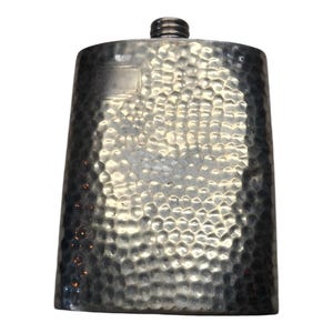 May include: A silver-coloured flask with a textured, hammered metal surface. The flask has a rounded top and a screw-on cap. The body of the flask is rectangular with rounded edges. The flask is designed to hold liquids.