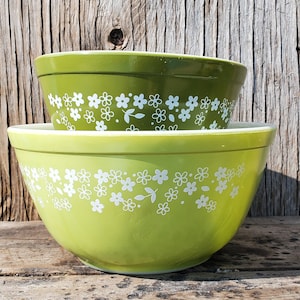 May include: Two green mixing bowls with a white floral pattern. The bowls are nested together.
