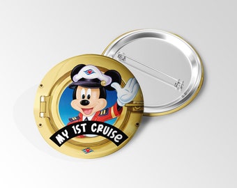 May include: A gold-colored button with a cartoon image of Mickey Mouse in a captain's uniform, waving from a porthole. The text "MY 1ST CRUISE" is displayed on a black banner. A second, similar button is visible.