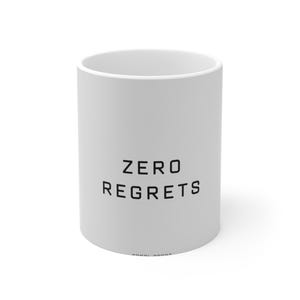 May include: A white ceramic mug with the words "ZERO REGRETS" printed in black, centered on the front. The mug has a simple, cylindrical shape and a glossy finish. The mug is designed for hot or cold beverages.